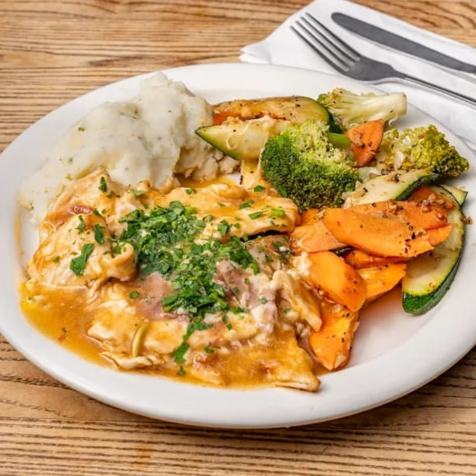 Chicken with gravy, mashed potatoes, and roasted vegetables on a white plate.